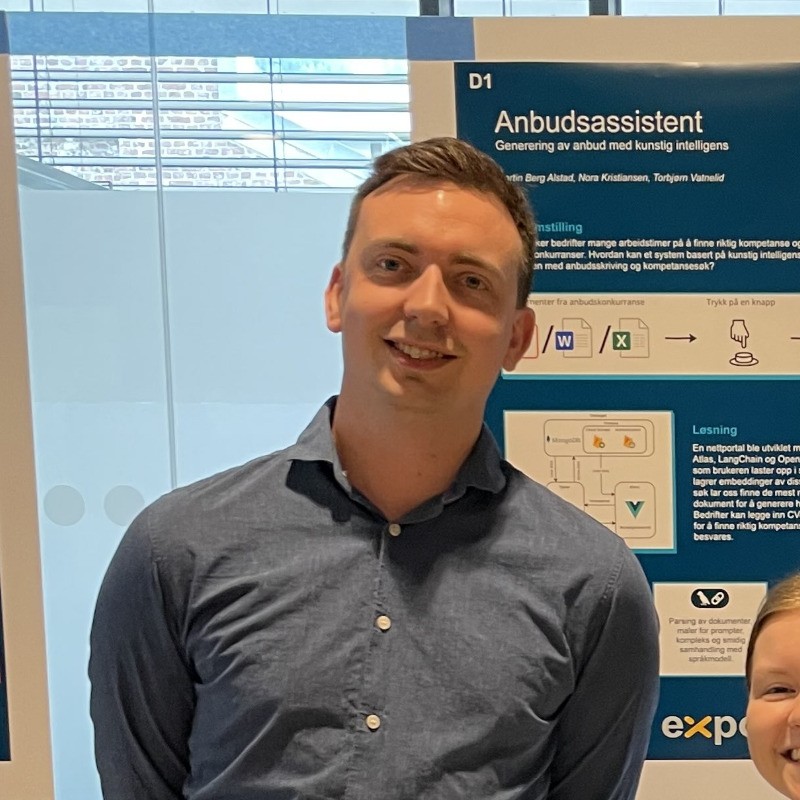 Me on a stand in front of a poster that says 'anbudsassistent'